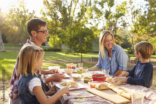 Fotografie Young white family enjoying a picnic at a table in a park