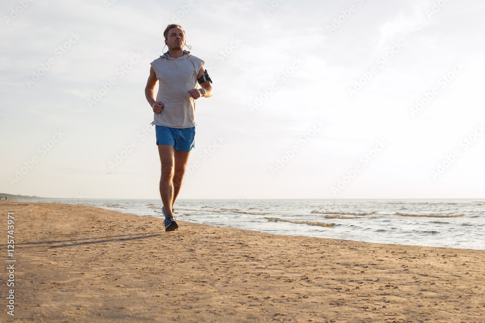 Handsome man running along the coast line