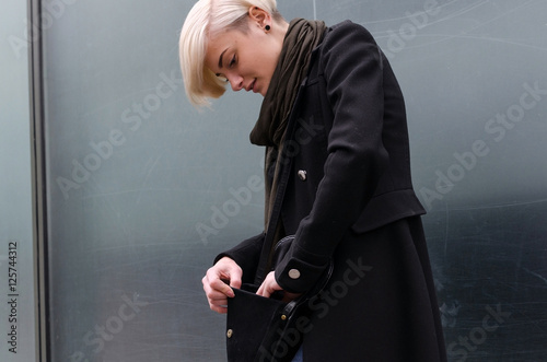 Young blonde woman is searching in her bag photo
