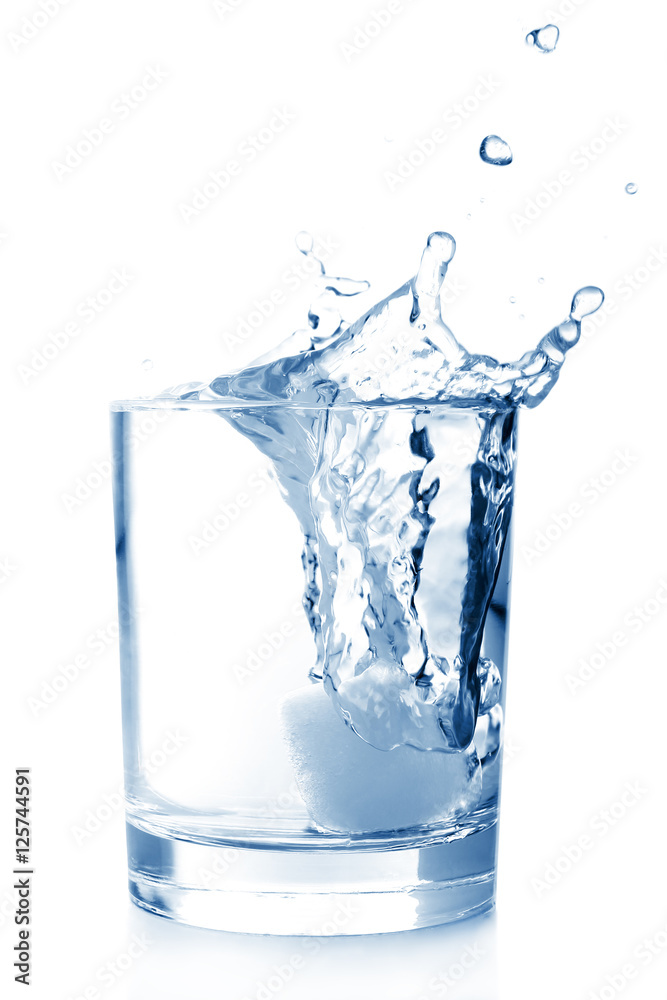 Ice in glass of water with splash on white background .
