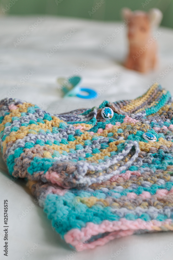 Crocheted baby sweater with a soother. Crocheted baby sweater with a soother.