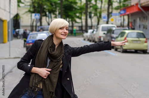 Young blonde woman catching the taxi 