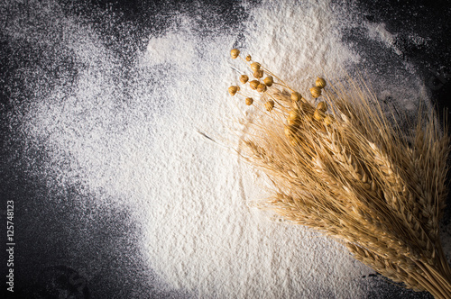 Scattered flour and wheat ears. On a black background.Top view. Flat lay.