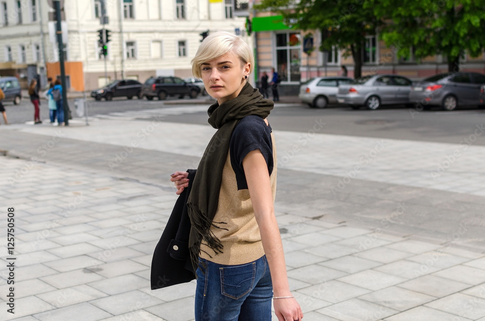 Young blonde girl walking on the city