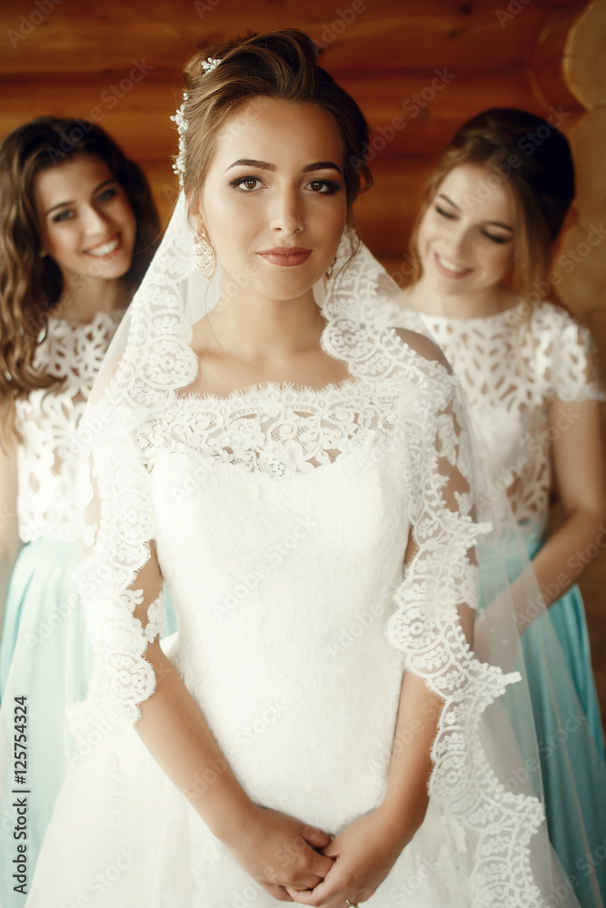 Bride holds her hands together standing in wooden room Bride holds her hands together standing in wooden room