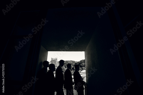 Silhouettes of five men standing in dark corridor
