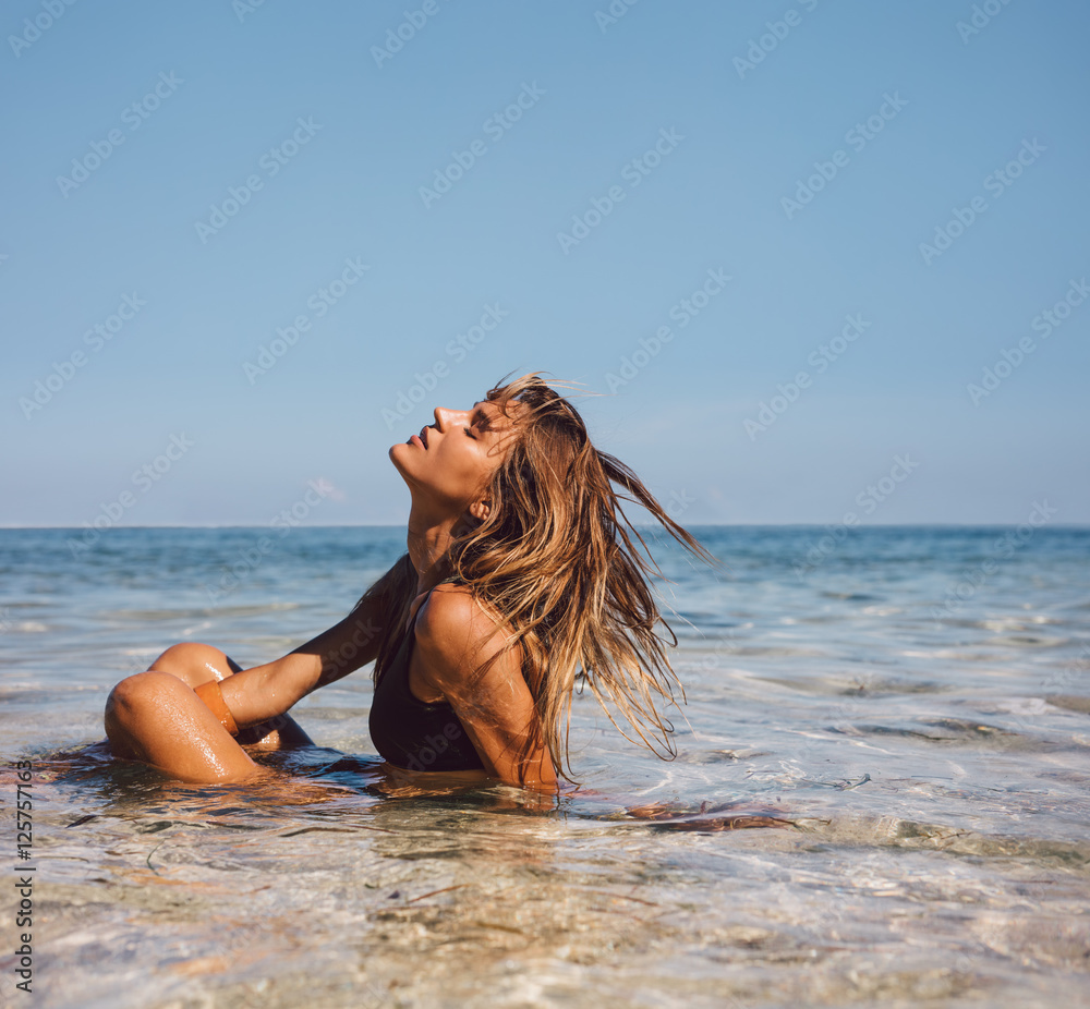 Naklejka premium Beautiful girl sitting in sea water