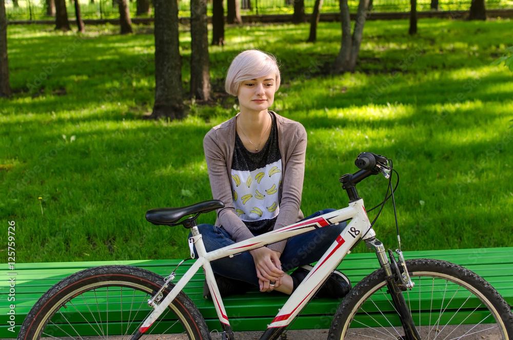 Naklejka premium Young girl with bicycle in the park
