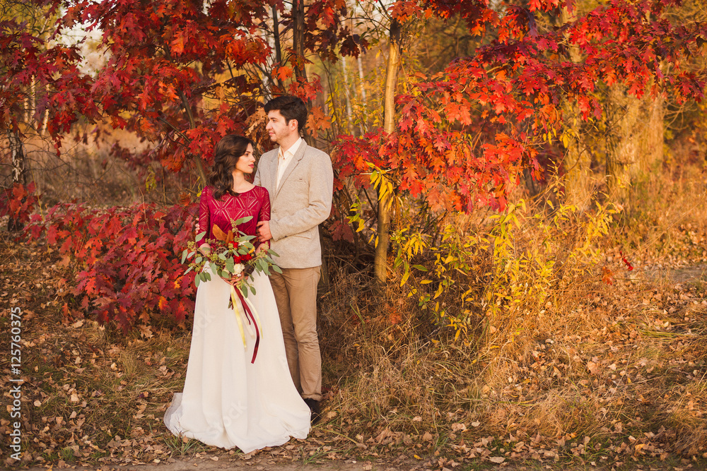 Stylish and romantic caucasian couple in the beautiful autumn park. Love, relationships, romance, happiness concept. Bouquet in girl's hands. Stylish and romantic caucasian couple in the beautiful autumn park. Love, relationships, romance, happiness concept. Bouquet in girl's hands.