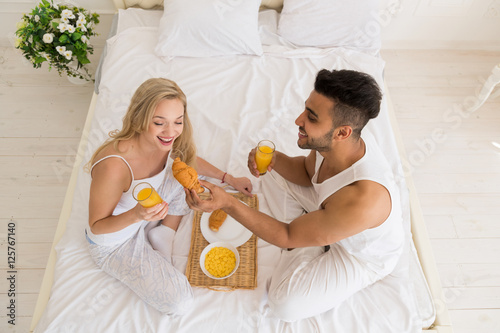 Young Couple Breakfast Sitting In Bed  Happy Smile Young Hispanic Man And Woman Morning Top Angle View Lovers Bedroom