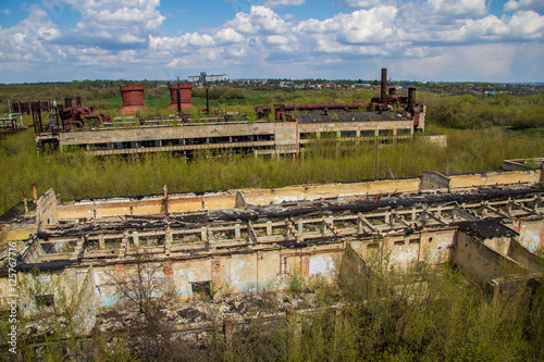 Abandoned factory of synthetic rubber overgrown by trees, ruins of buildings