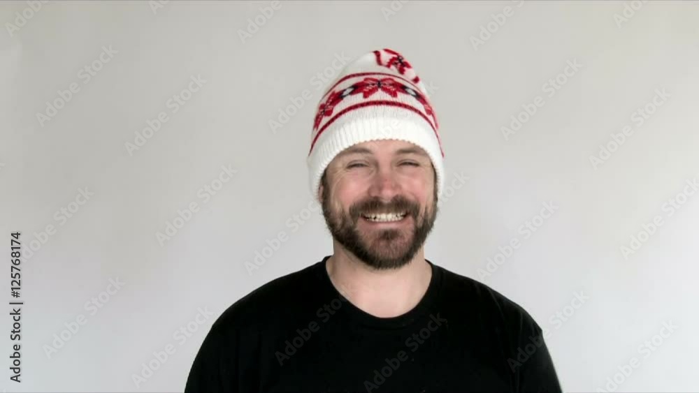 Model released man in studio puts on a funny winter hat with big smiles. Model released man in studio puts on a funny winter hat with big smiles.