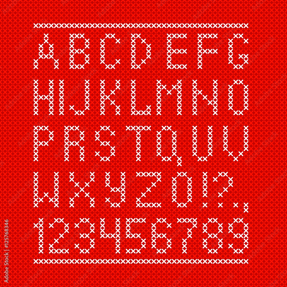 Embroided by cross stitch english alphabet with numbers and symbols on red cloth texture.