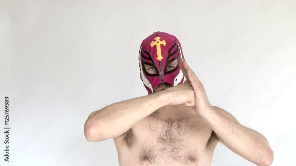 Model released man in studio wearing red lucha libre mask wrestles and challenges viewer.