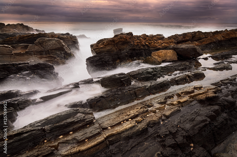 Mystical rock pool on a rocky ocean coastline in the early morning on an overcast day