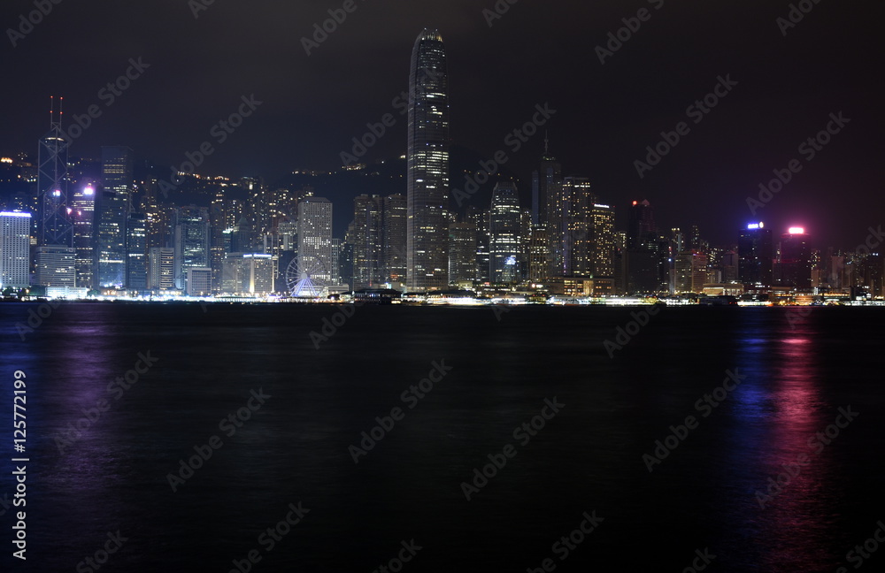 Beautiful night view of Hong Kong island skyline across Victoria Harbour from Avenue of Stars at Kowloon. Skyscrapers on waterfront in downtown. Global financial center.