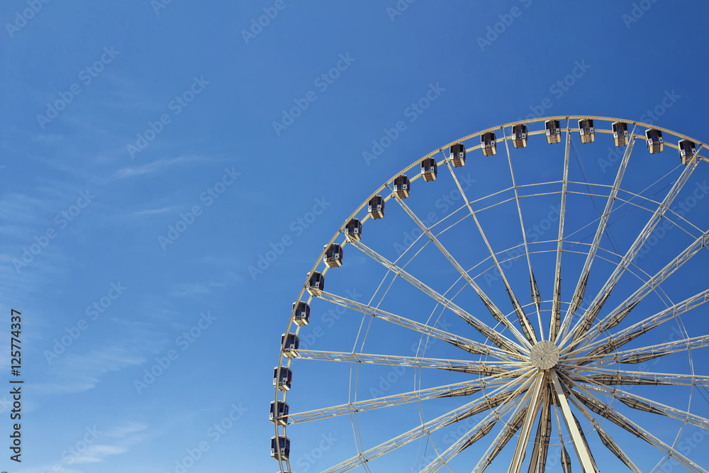 Half view of ferris wheel with blue sky background at Jardin Des Tuileries in Paris.