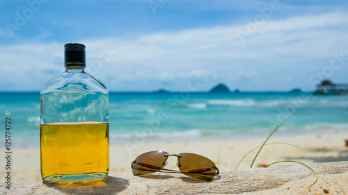 Fotografi Beach party. Holiday fun concept. Bottle of rum and sunglasses w