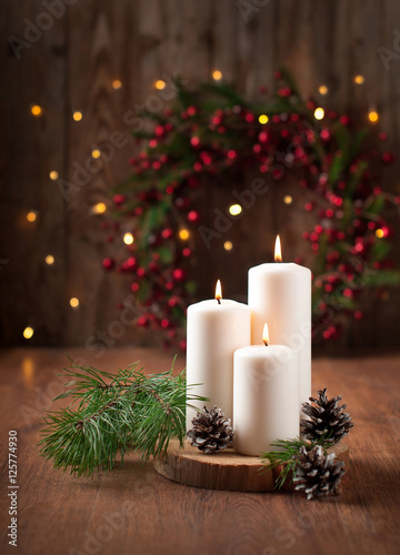 burning candles wooden table pine branches cones background with Christmas wreath and lights