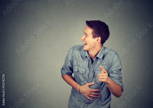 Tableau sur toile Portrait laughing young man pointing with finger