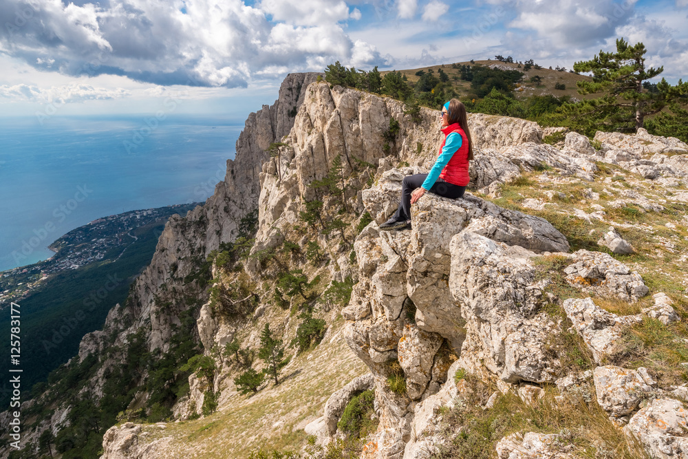 Girl sits on the edge of the cliff