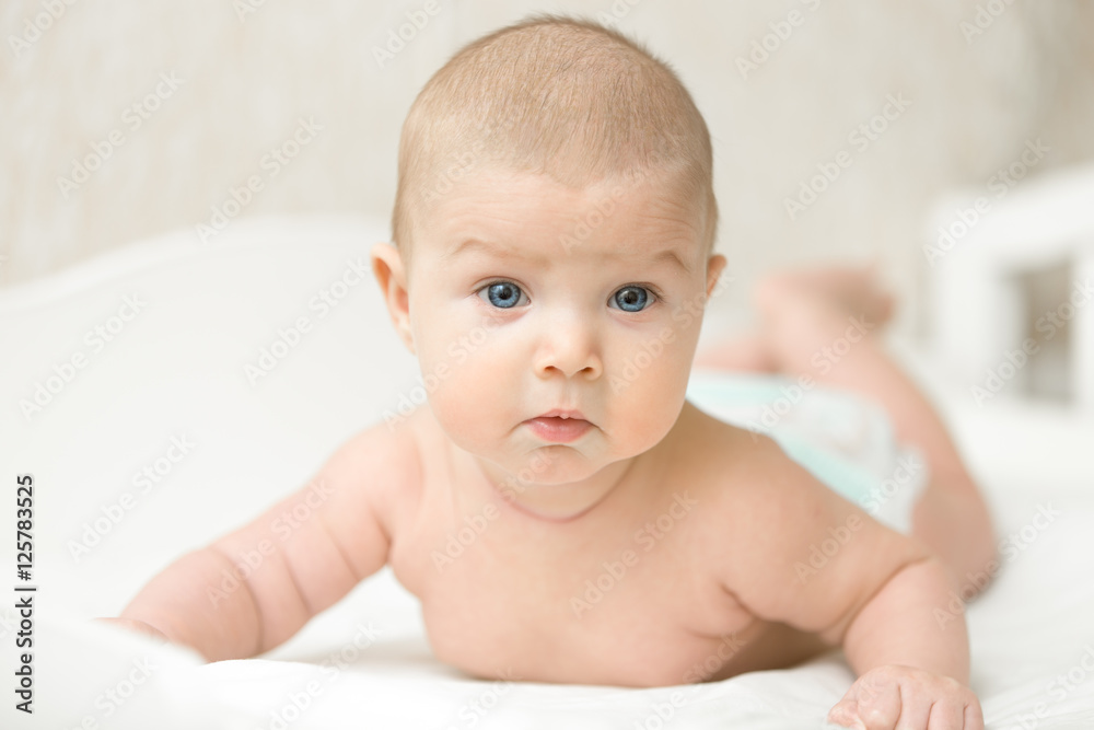 Portrait of a cute baby making questionable funny face, raises head and chest, put on tummy. Family concept photo, lifestyle Portrait of a cute baby making questionable funny face, raises head and chest, put on tummy. Family concept photo, lifestyle