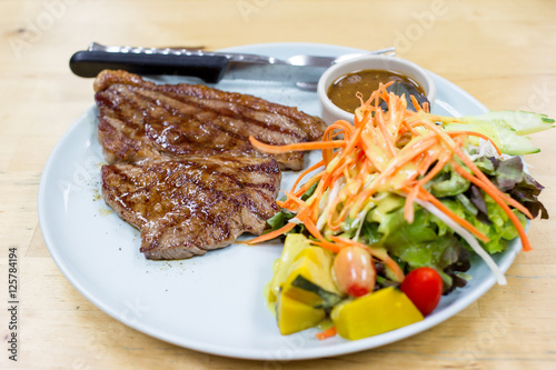 Medium well beef steak with salad close up.