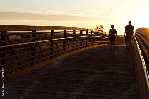 Young Couple Walking for Health-a young, healthy couple walking across a footbridge in evening light