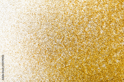 Golden glitter sand texture on white, abstract background.