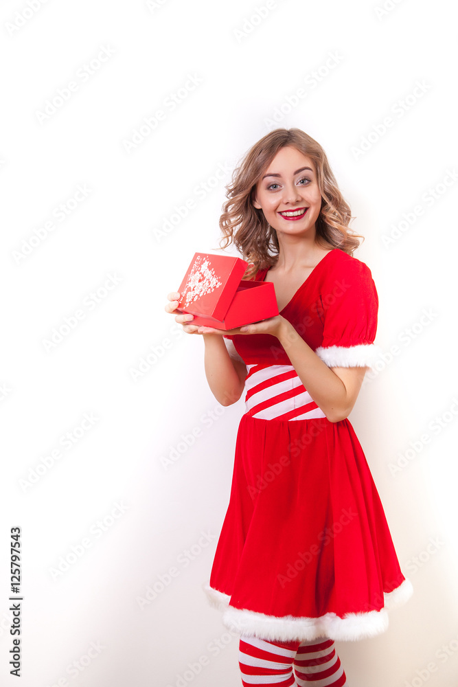 Beautiful Happy girl in Santa Claus clothes opens a gift Beautiful Happy girl in Santa Claus clothes opens a gift