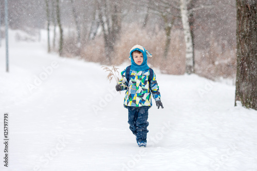 Cute little boy with backpack, going on a ski holiday, walking i