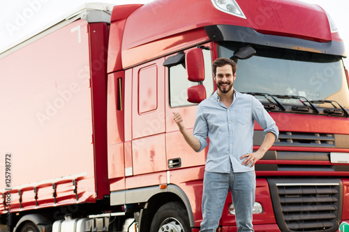 masculine truck driver in jeans with his truck behind
