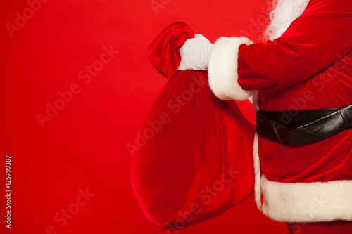 Santa Claus hand holding red sack full of presents over © satyrenko