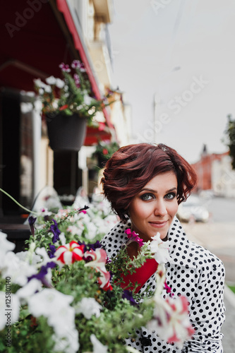 Close-up of charming smiling elegant woman with flower pot on the background of city street