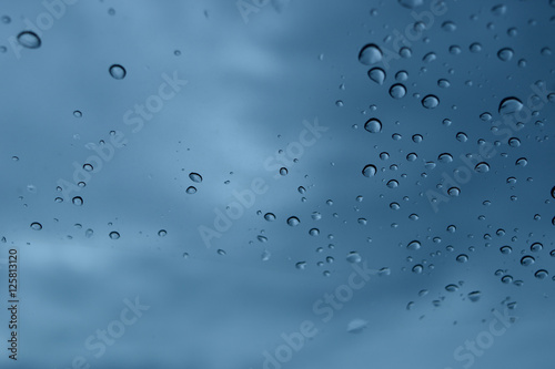 rain drops on glass. black cloud background, view in car