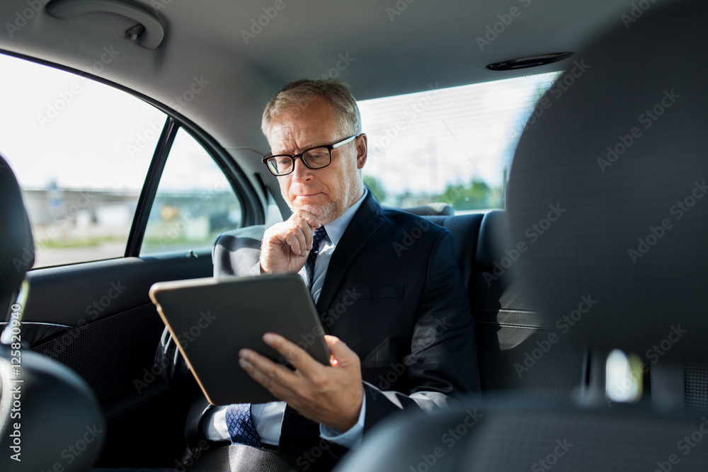 senior businessman with tablet pc driving in car