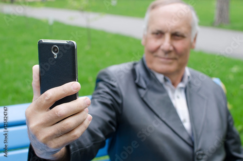 Aged man is using cellphone in the park