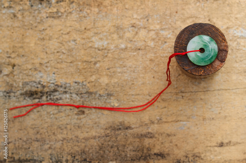 Jade stone with red rope on wooden background