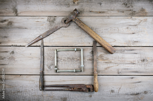 The concept of a house under construction. Old wooden desktop. Old rusty carpentry tools. Horizontal mockup