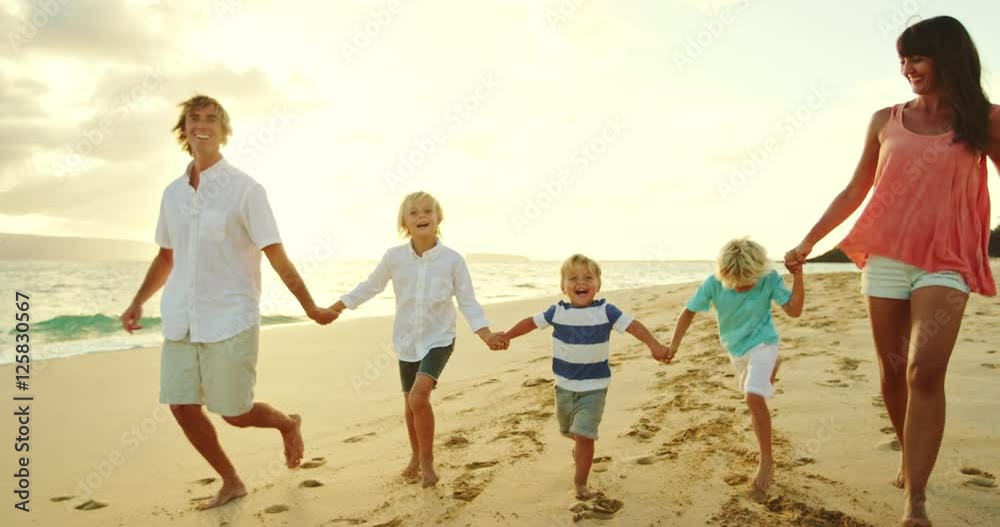 Happy family walking down the beach at sunset Happy family walking down the beach at sunset
