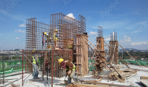 Construction workers fabricating steel reinforcement bar at the construction site in Malacca, Malaysia. The reinforcement bar was ties together using tiny wire.  
 