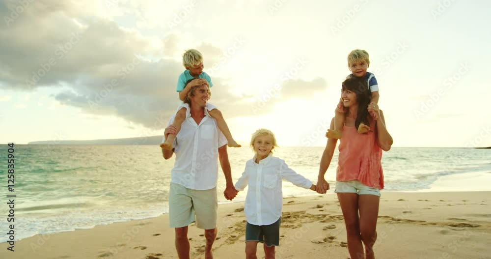 Happy family walking down the beach at sunset