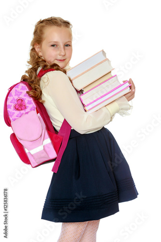 Girl schoolgirl with a satchel behind shoulders and books in han