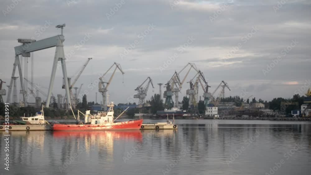 red ship on the river in front of cranes on a beautiful dawn red ship on the river in front of cranes on a beautiful dawn