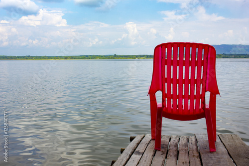 red chair on wooden bridge near sea beach