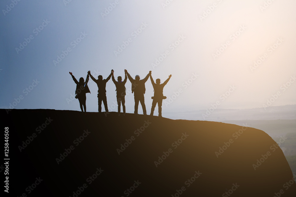 silhouette group people hold hands together on the top of the mountain