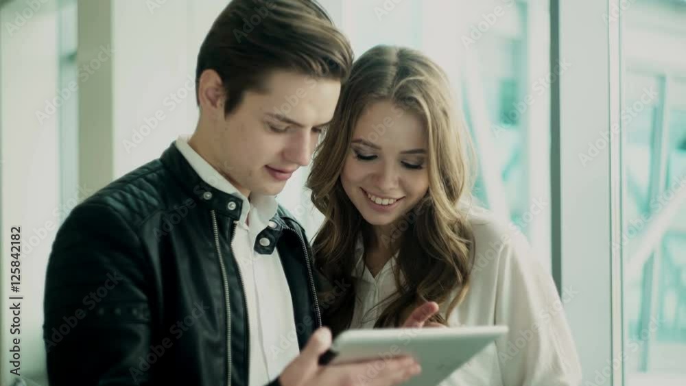 Young man and woman.They are discussing some business matters using tablet computer Young man and woman.They are discussing some business matters using tablet computer