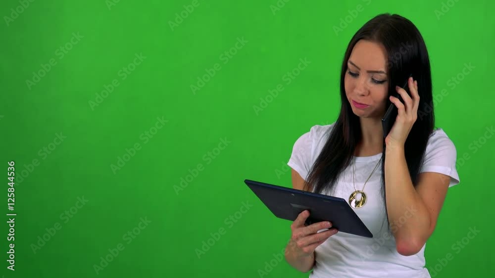 young pretty woman works on tablet and phone with smartphone - green screen 