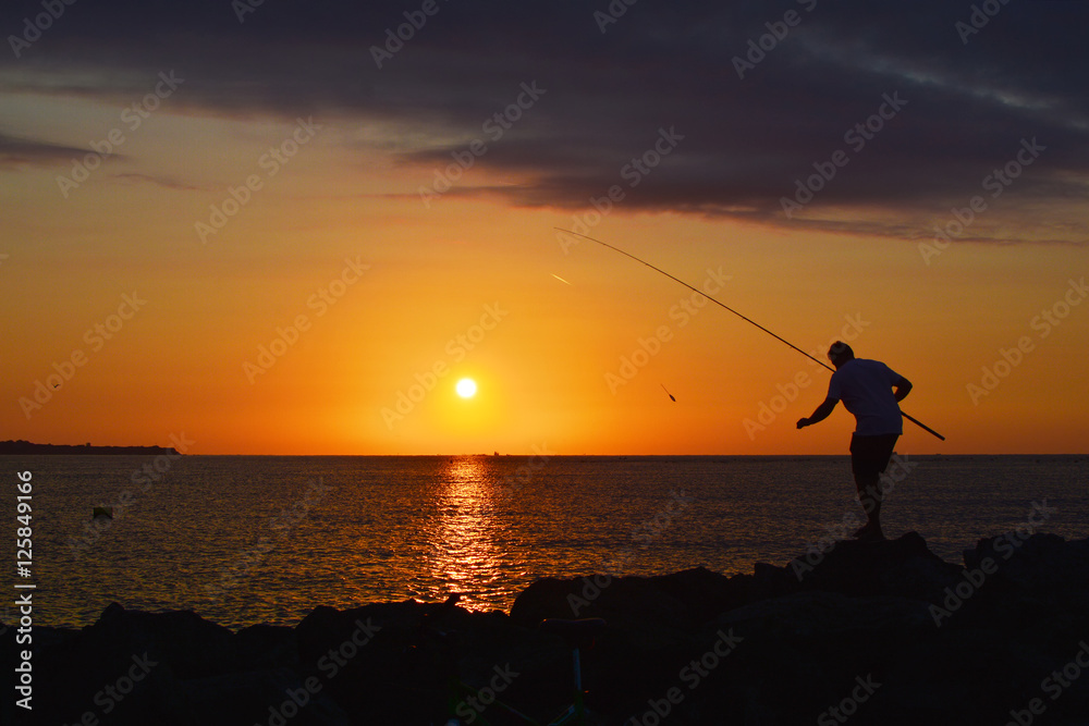 Silhouette of fisherman by the sea on sunrise 