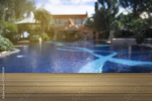 Wooden board empty table against of blurred swimming pool background. Perspective brown wood over swiming pool can be used for display or present your products.Mock up your products